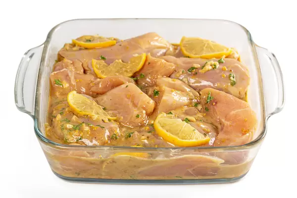 Marinated chicken pieces in a glass baking sheet, ready to bake