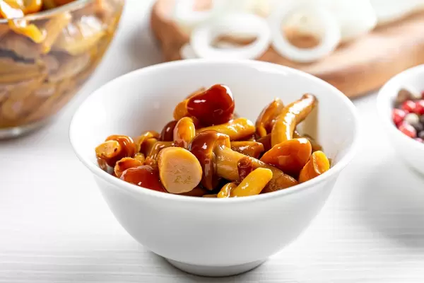 Marinated mushrooms in a bowl on white wooden table (Flip 2019)