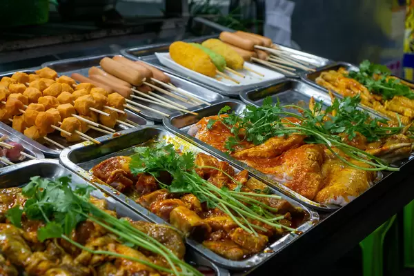 Marinated Pork and Chicken, Meatballs, Hot Dogs and Corndogs on Skewers at a Barbecue Street Food Cart at a Night Market in Can Tho, Vietnam
