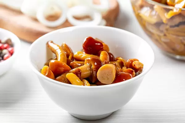 Marinierte Pilze in einer weißen Schale auf einem gedeckten Tisch