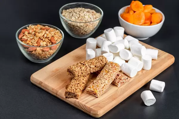 Marshmallows, granola bars, oatmeal and dried apricots on a dark background