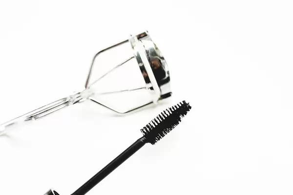 Mascara and eyelash curler on white background