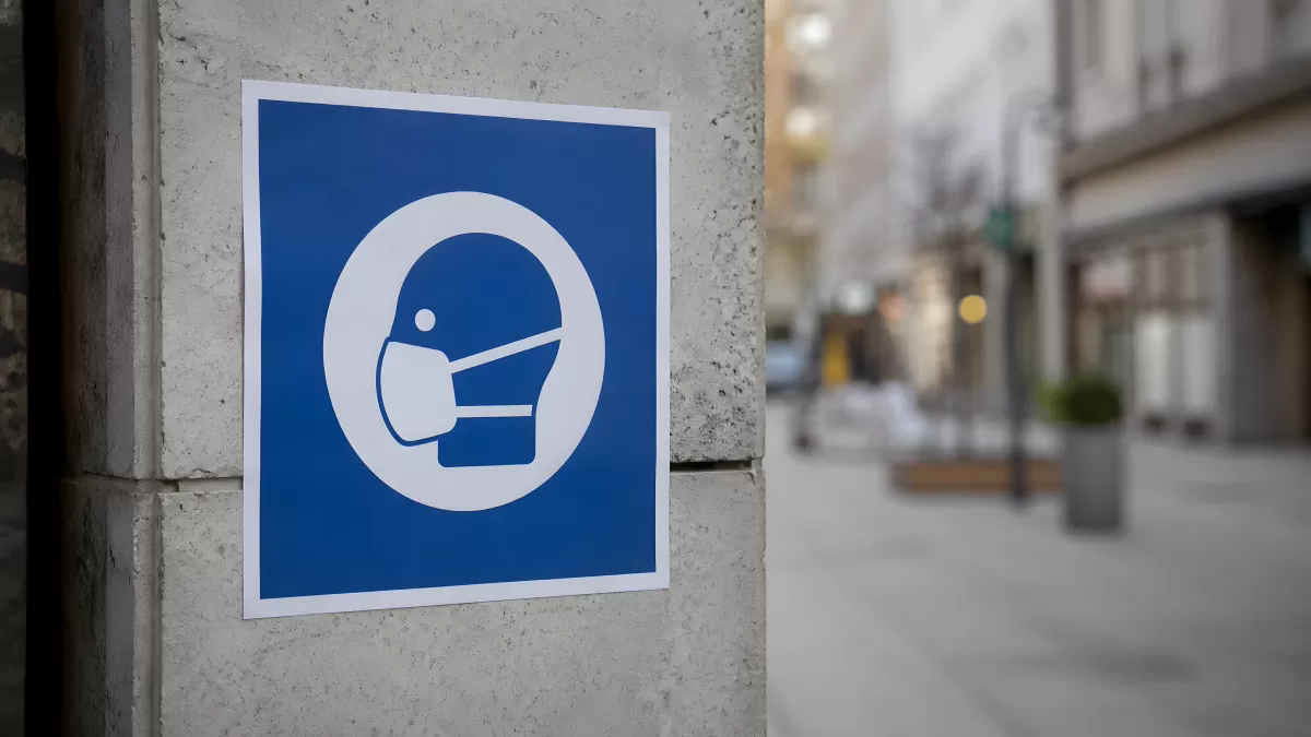 Maskenpflicht-Schild an Hauswand in Stadtstraße
