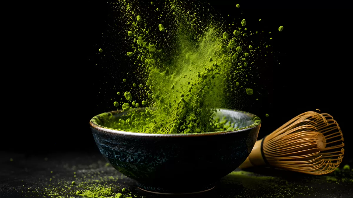 Matcha-Pulver explodiert aus schwarzer Teeschale