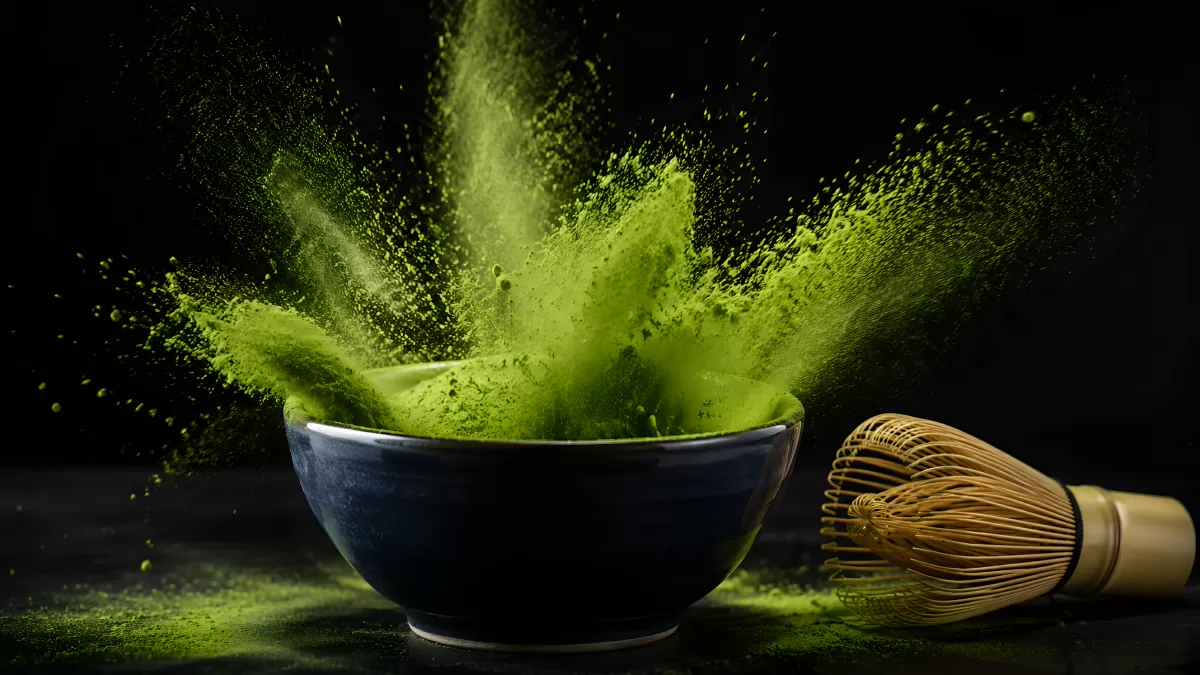 Matcha-Pulver stäubt aus blauer Keramikschale