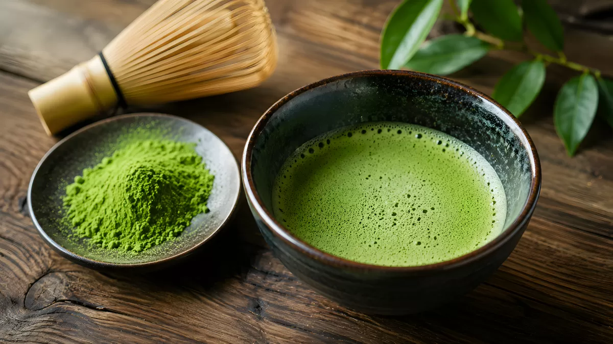 Matcha-Tee in Schale mit Pulver und Bambusbesen