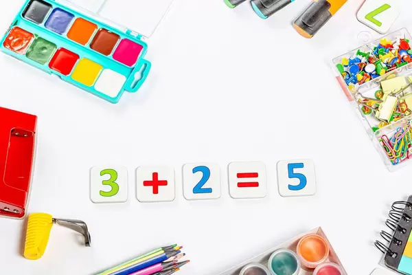 Mathematikaufgabe für Schüler umgeben von bunten Schreib-, Mal- und Bastelmaterial