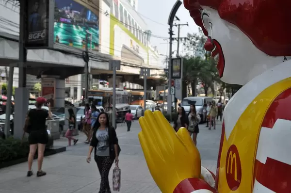 McDonald's Clown mit zusammengelegten Händen und Passanten im Hintergrund