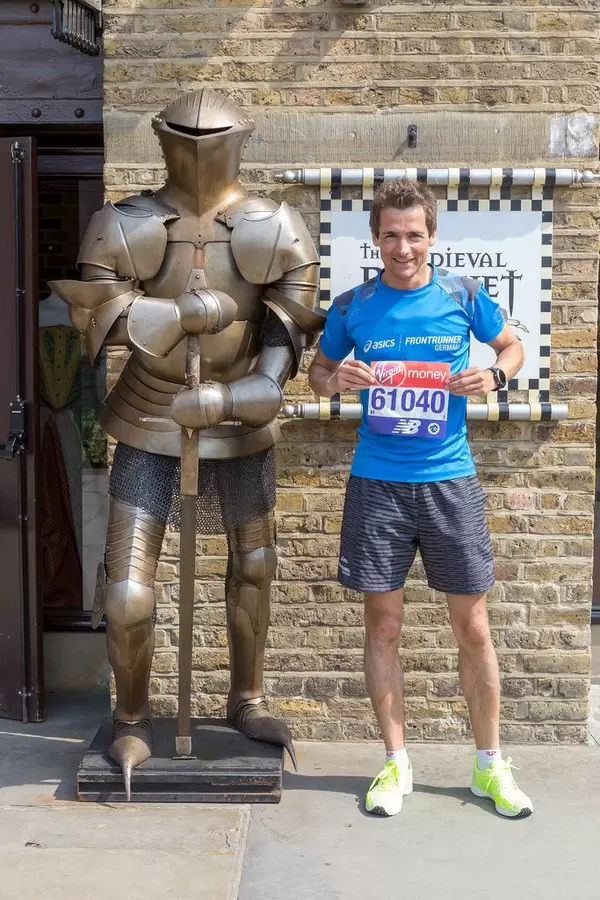 Me alongside a knight's armor with London Marathon bib number in hands