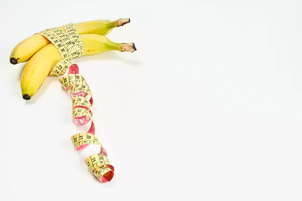 Measuring tape wrapped around bananas. Concept of penis enlargement, healthy eating, dieting and weight loss