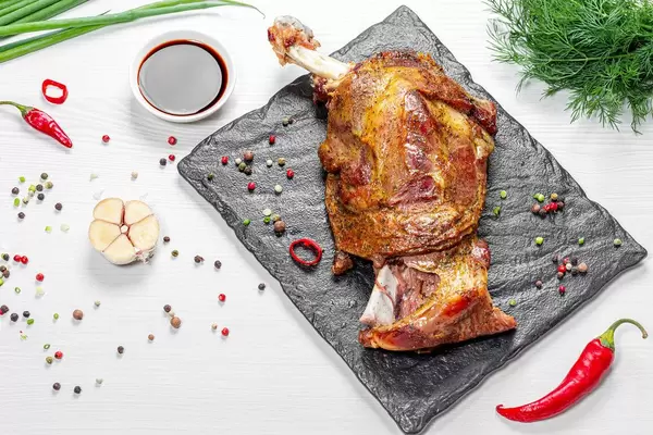 Meat baked with bone with spices and sauce on a white table. Top view (Flip 2019)
