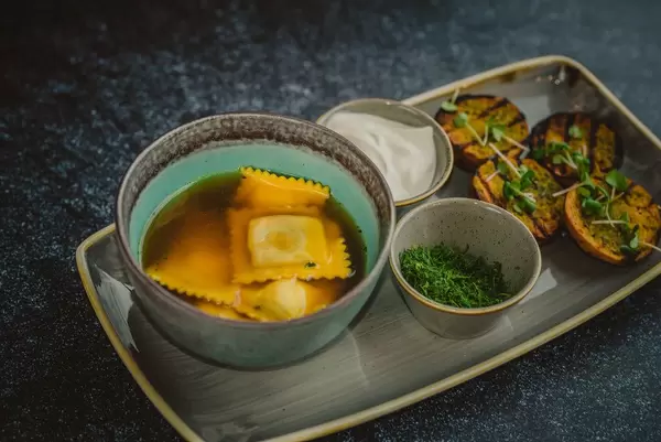 Meat broth with ravioli in a bowl closeup.