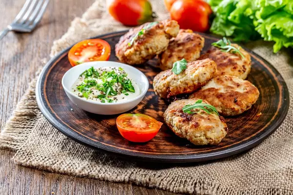 Meat cutlets with sauce and herbs in a brown plate on a burlap