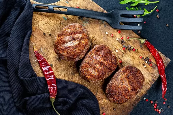 Meat cutlets with spices and chili on an old kitchen Board. Top view