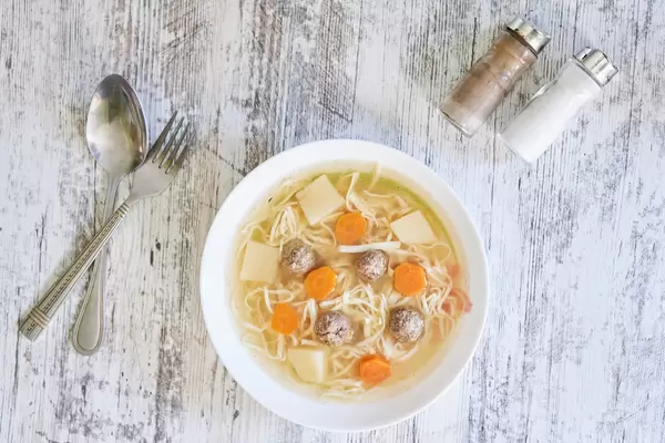 Meatball soup with noodles potato on wooden surface
