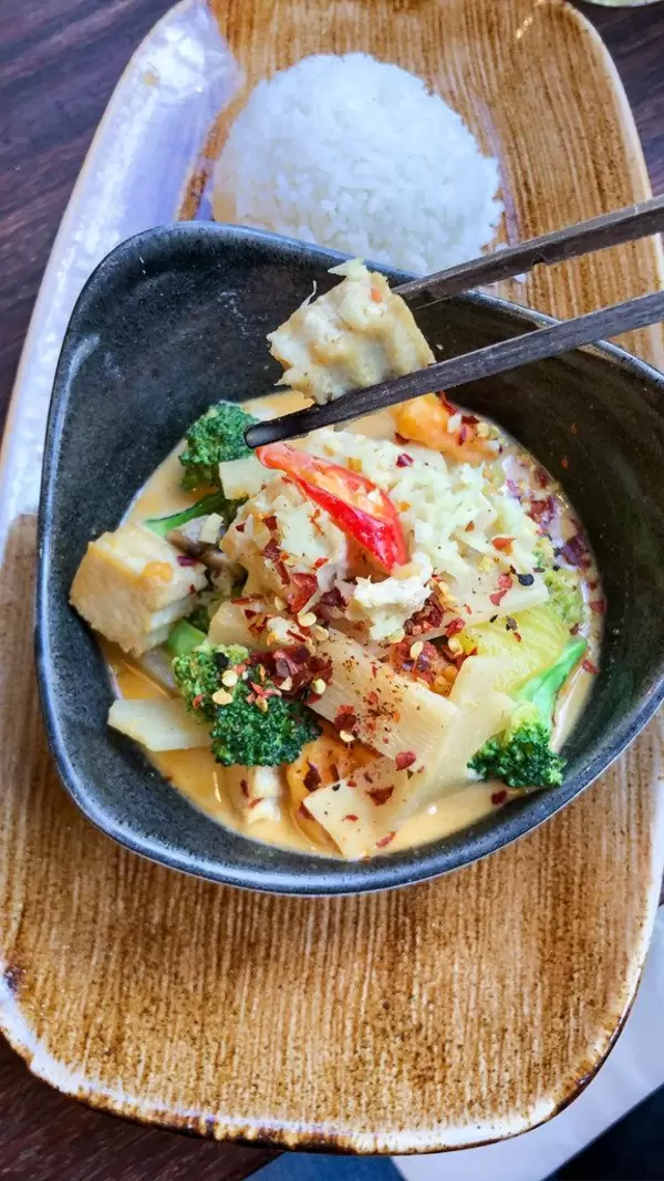 Meatless Lunch: vegan vegetable thai curry with broccoli, bamboo, coconut milk and white cabbage, with chopsticks, next to white rice