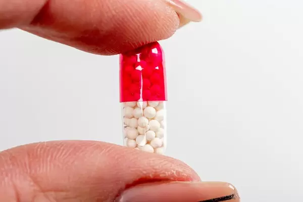 Medical care concept. Capsule with medical granules in a female hand close-up