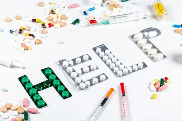 Medical care need concept. Medical drugs and syringes on a white background with the word help