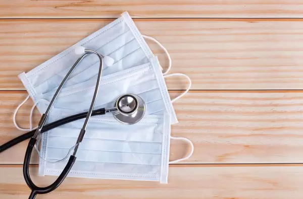 Medical disposable masks with stethoscope on wooden background