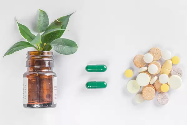 Medical drugs concept, bottle with green leaves and heap of pills