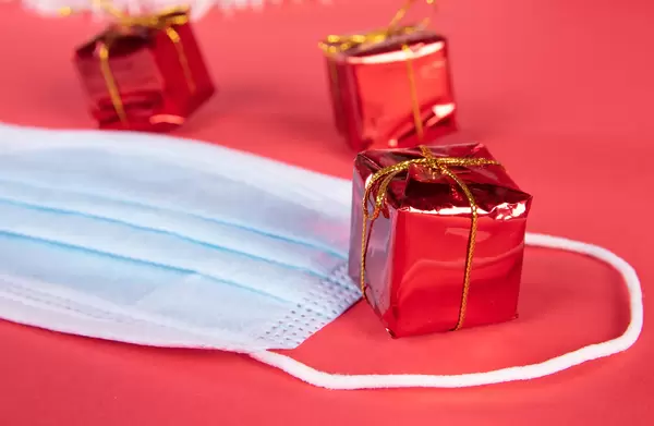 Medical face mask and Christmas gifts on red background