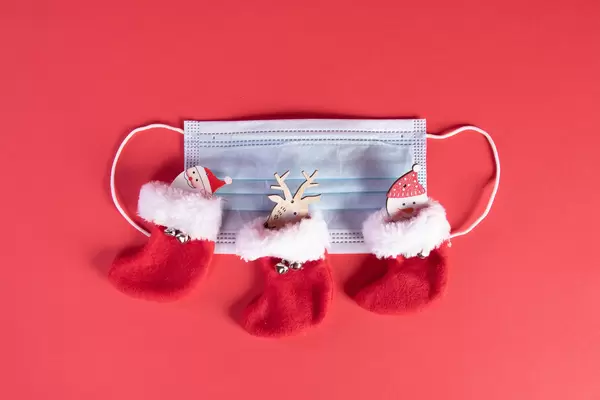 Medical face mask and christmas socks on red background