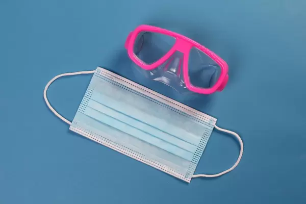 Medical face mask and diving mask on blue background