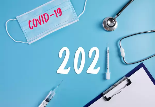 Medical face mask, clipboard, stethoscope and syringe with 2021 text on blue background