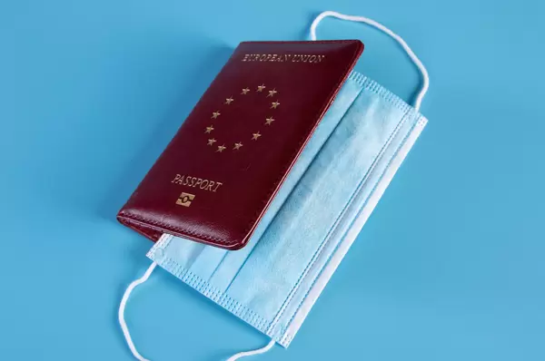 Medical face mask inside passport on blue background