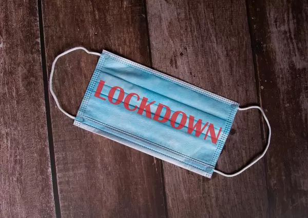 Medical face mask with Lockdown text on wooden background