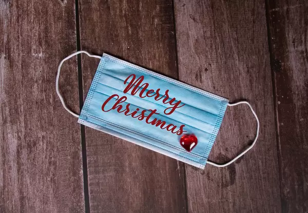 Medical face mask with Merry Christmas text on wooden background