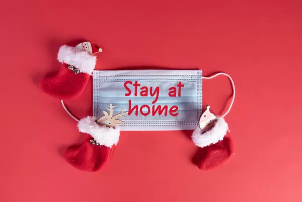 Medical face mask with Stay at home text and christmas socks on red background