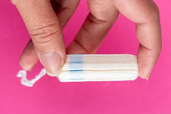 Medical female tampon on a pink background in women's hand