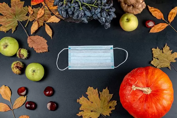 Medical mask on an autumn background with a pumpkin. Personal protection concept in autumn season