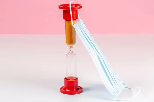 Medical mask with an hourglass. The concept of waiting