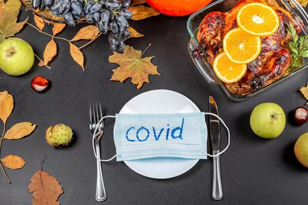 Medical mask with the inscription Covid on a white plate. Thanksgiving table top view