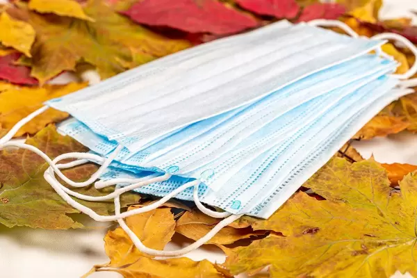 Medical masks on a background of dry autumn leaves. Personal protection concept in the autumn season
