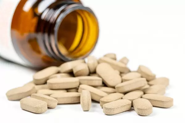 Medical pills scattered from a jar on a white background