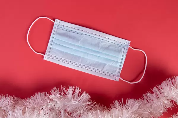 Medical protective face mask and Christmas decorations on red blue background