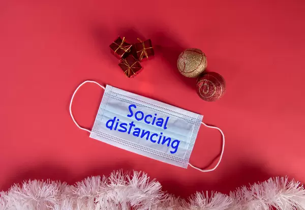 Medical protective face mask with Social Distancing text and Christmas decorations on red blue background