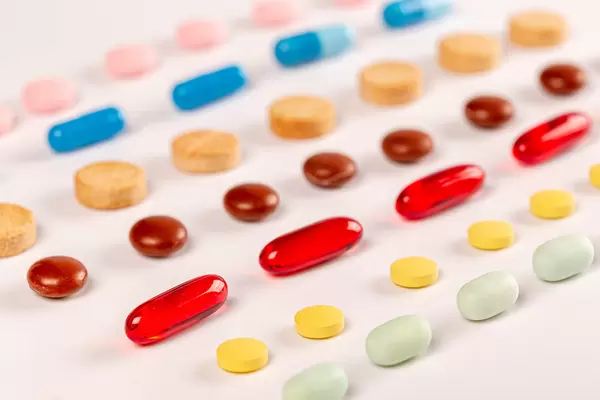 Medical tablets and capsules in different colors on white