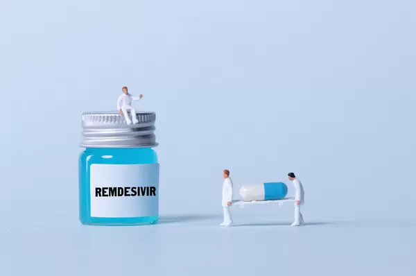 Medical workers sitting on a bottle with blue fluid and Remdesivir text