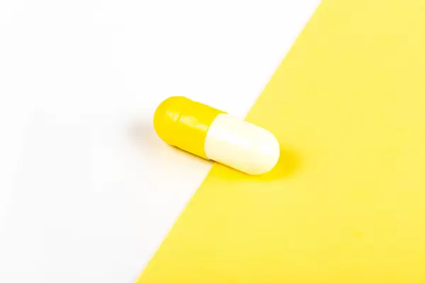 Medicinal capsule on yellow and white background