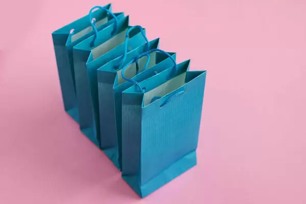 Mehrere blaue Geschenktüten vor einem rosafarben Hintergrund
