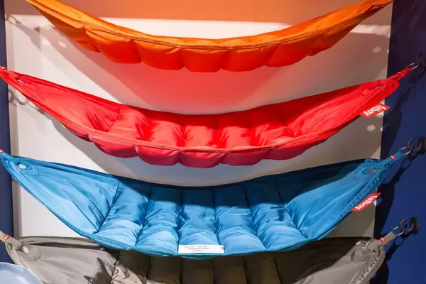 Mehrere Hängematten aus Stoff für mehrere Personen übereinander an Haken aufgespannt