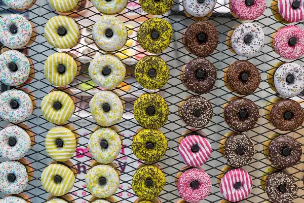 Mehrere Reihen von bunten Donuts mit verschiedenen Glasuren