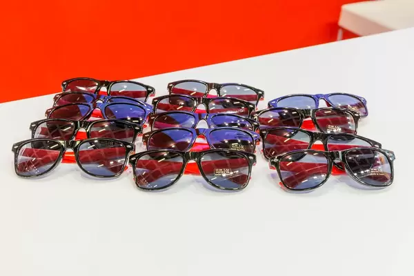 Mehrere Sonnenbrillen mit rotem Bügel, auf einem weißen Tisch