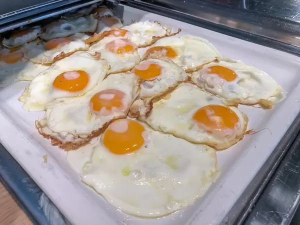 Mehrere Spiegeleier auf einem Wärmetablett am Frühstücksbüfett