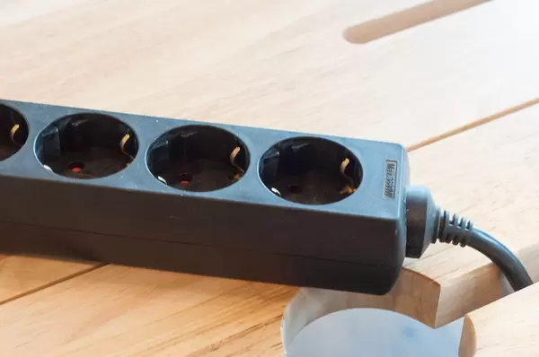 Mehrfachsteckdose in schwarz auf einem Holztisch