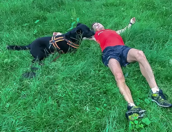 Mein Schwarzer Labrador und ich liegen im Gras